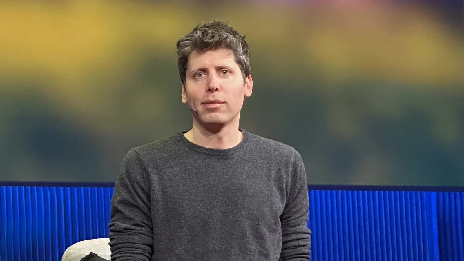 Sam Altman sentado en un sillón, con micrófono de diadema, durante una intervención en TED.