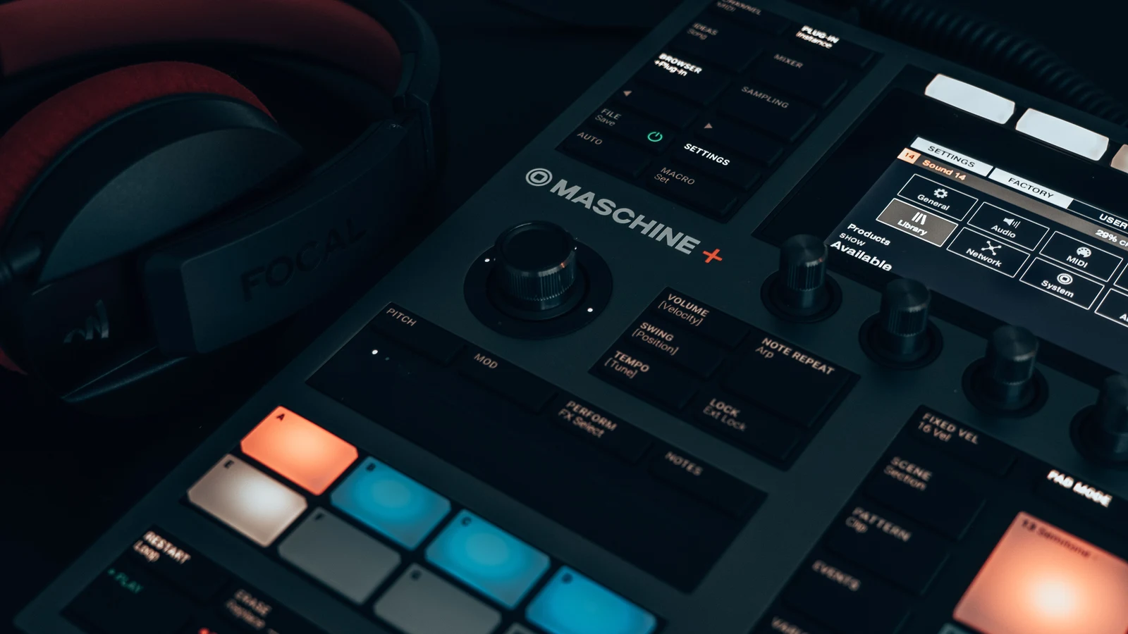 Auriculares junto a un equipo de producción musical con botones y controles iluminados.