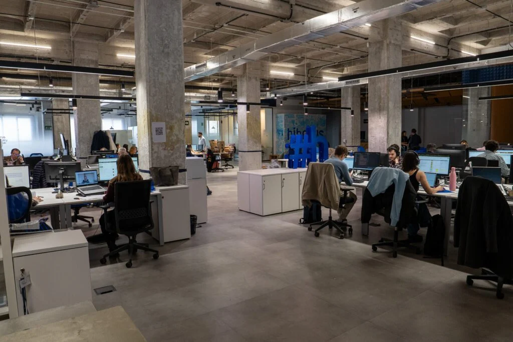 Espacio de trabajo de Karmina con mesas y grandes ventanales.
