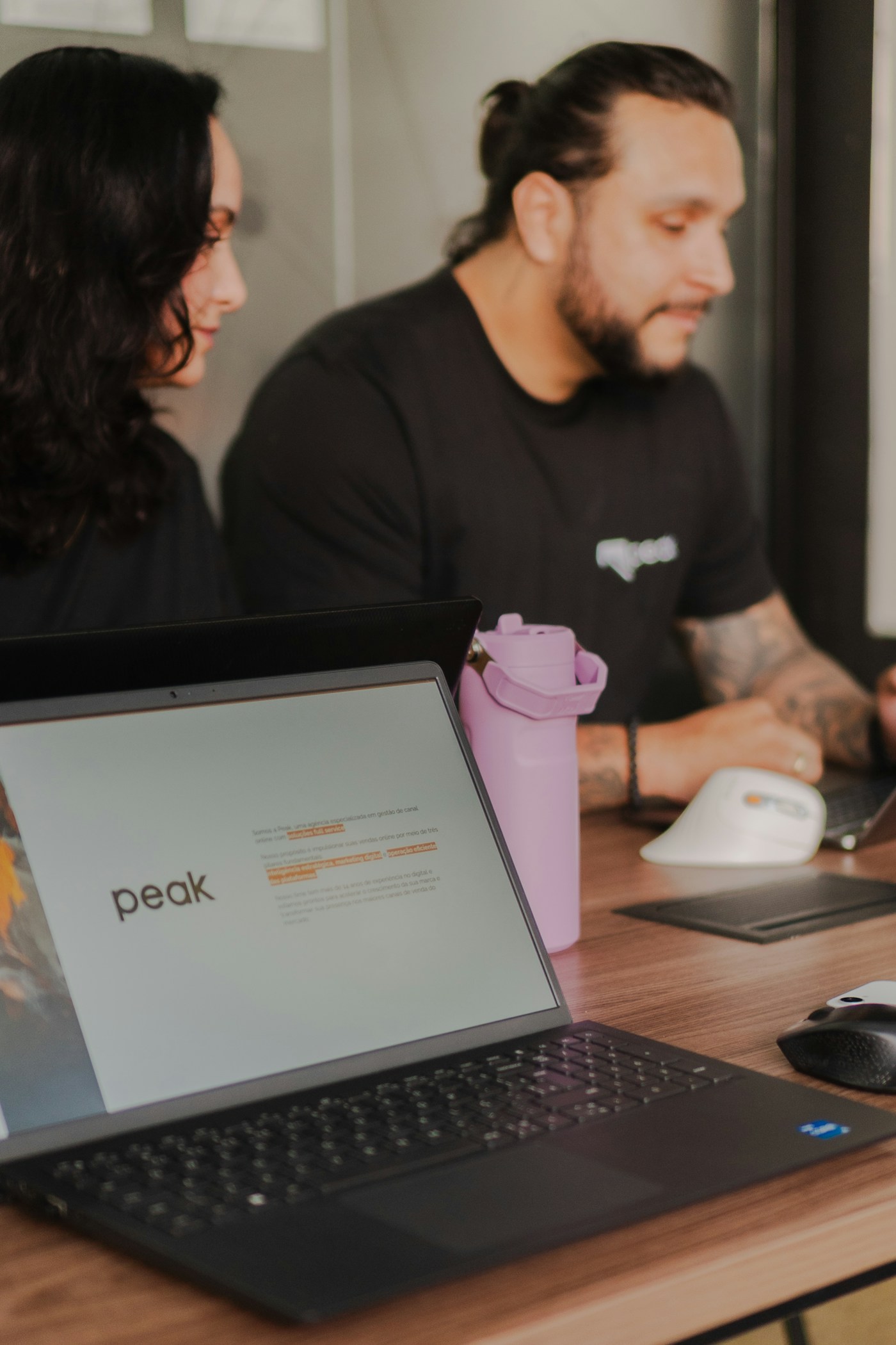 Mesa de trabajo compartida con portátiles y cuadernos.
