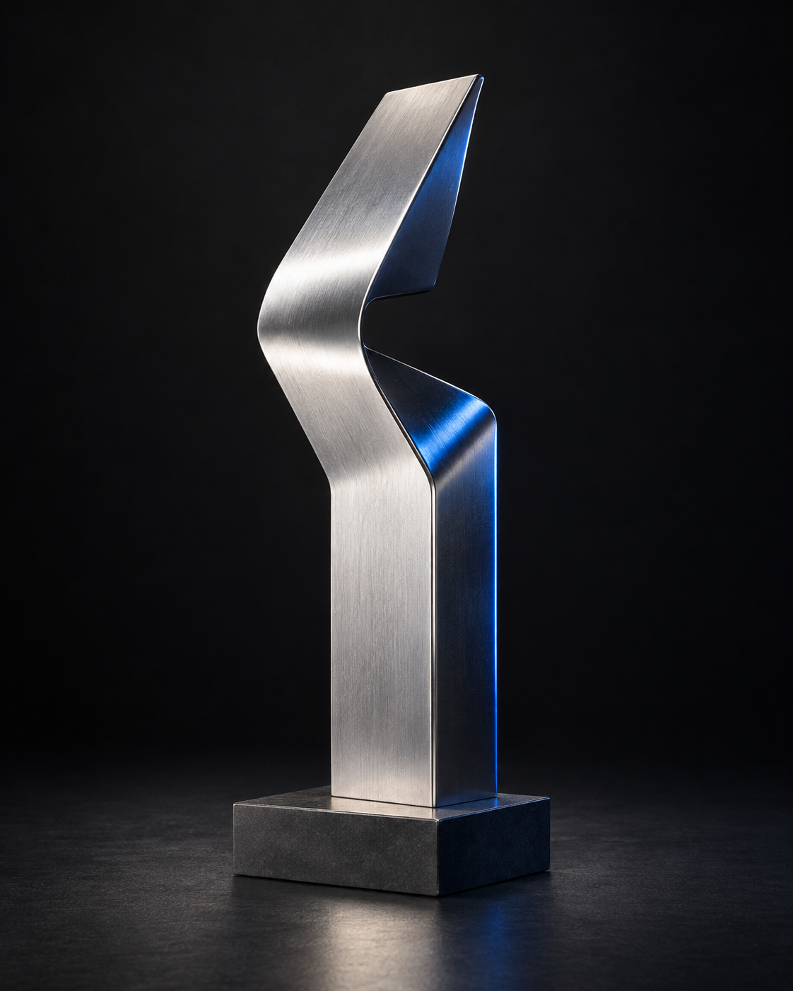 Propuesta de La Contra: escultura de metal plateado plegada en sentido contrario sobre una base oscura