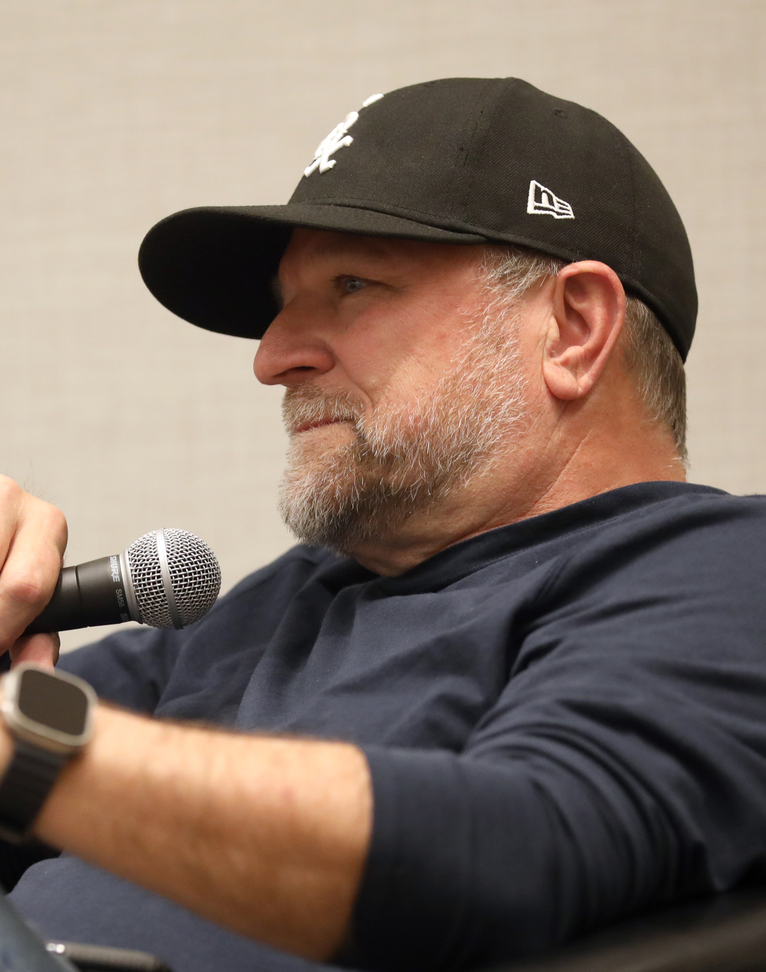 Ned Luke, con gorra negra, interviene con un micrófono en un encuentro público.