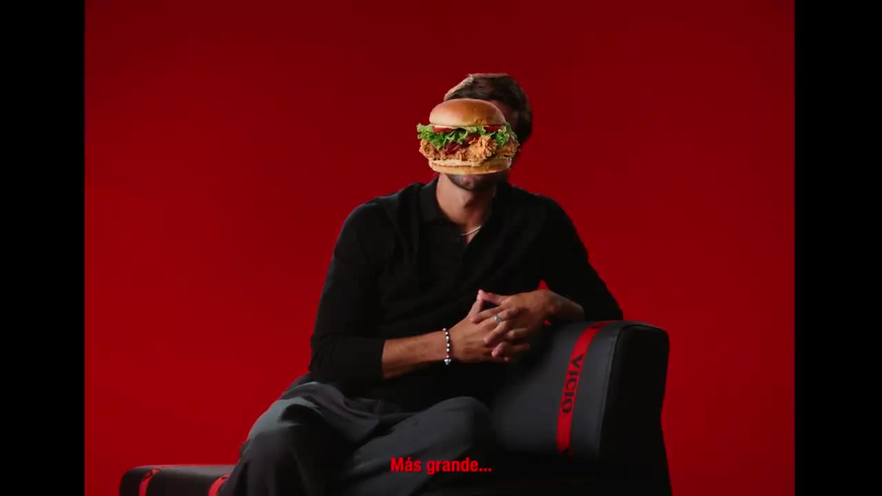 Ferran Torres sentado ante un fondo rojo, con una hamburguesa superpuesta tapándole parte de la cara.