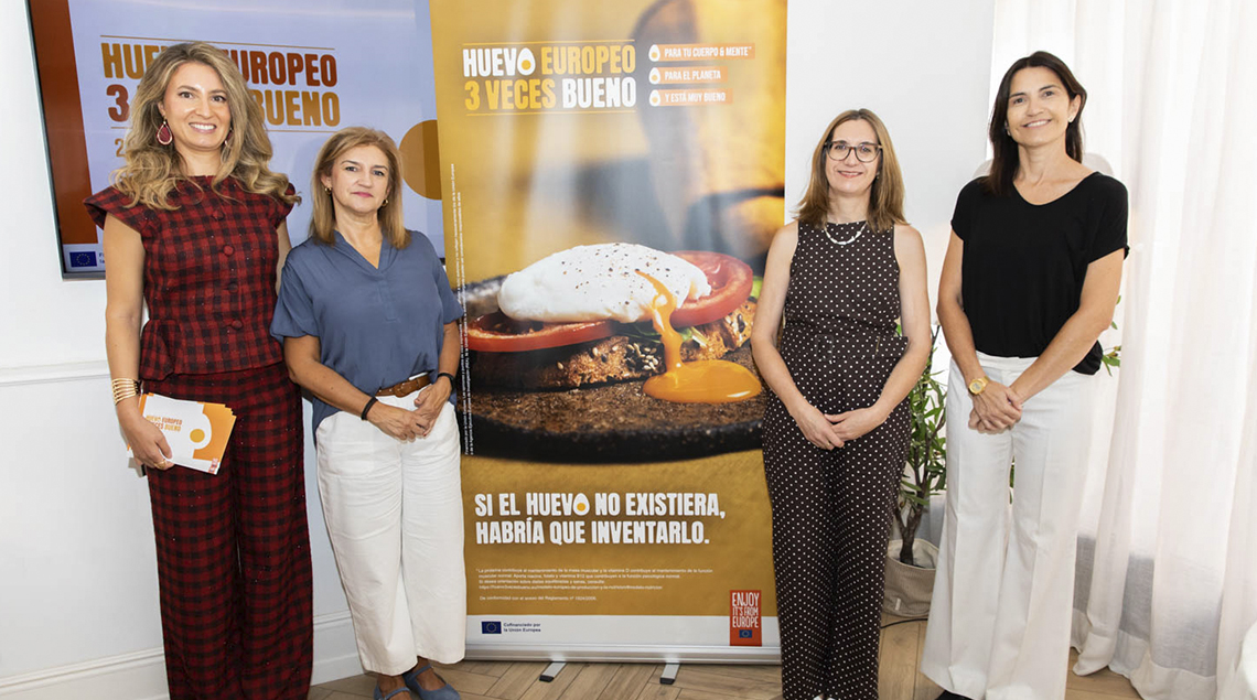 Cuatro participantes posan ante el cartel de la campaña de Inprovo.