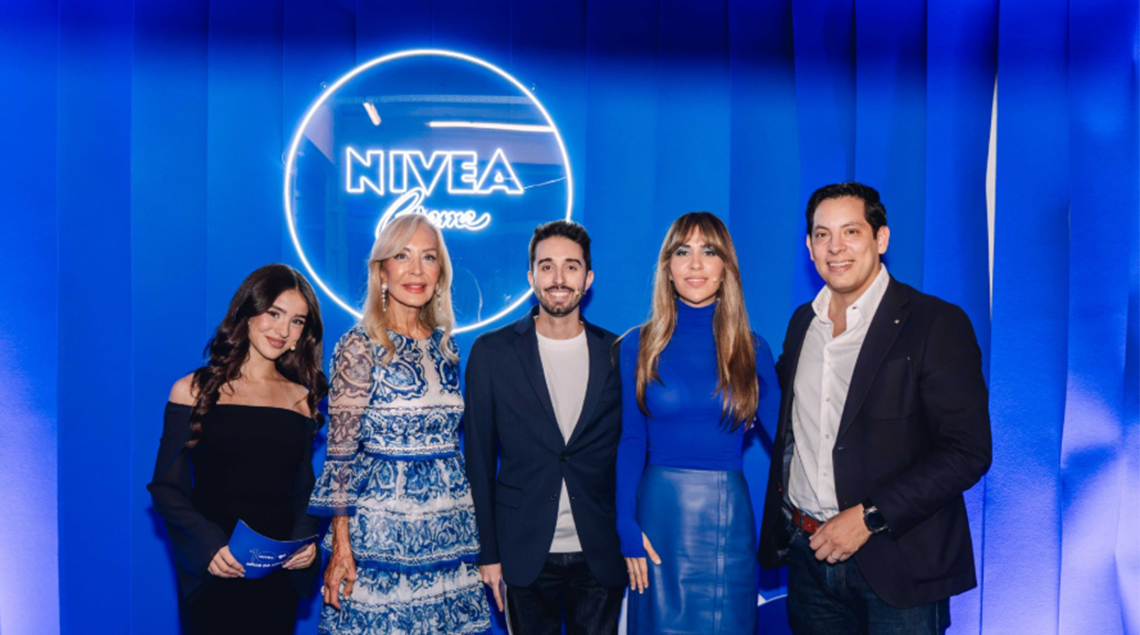 Cinco invitados posan ante la lata azul iluminada en un acto de Nivea.
