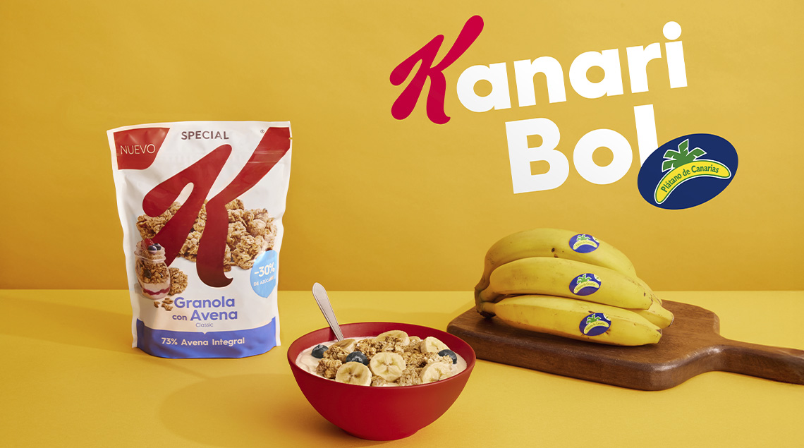 Cuenco de cereales, caja de Special K y plátanos sobre fondo amarillo.