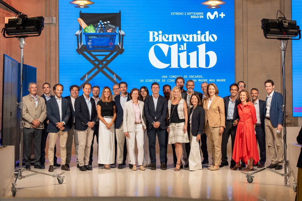 Grupo de representantes ante el escenario y la pantalla de «Bienvenido al Club».