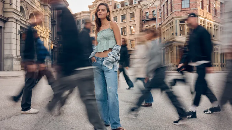 Una modelo con conjunto vaquero de American Eagle en una calle concurrida.