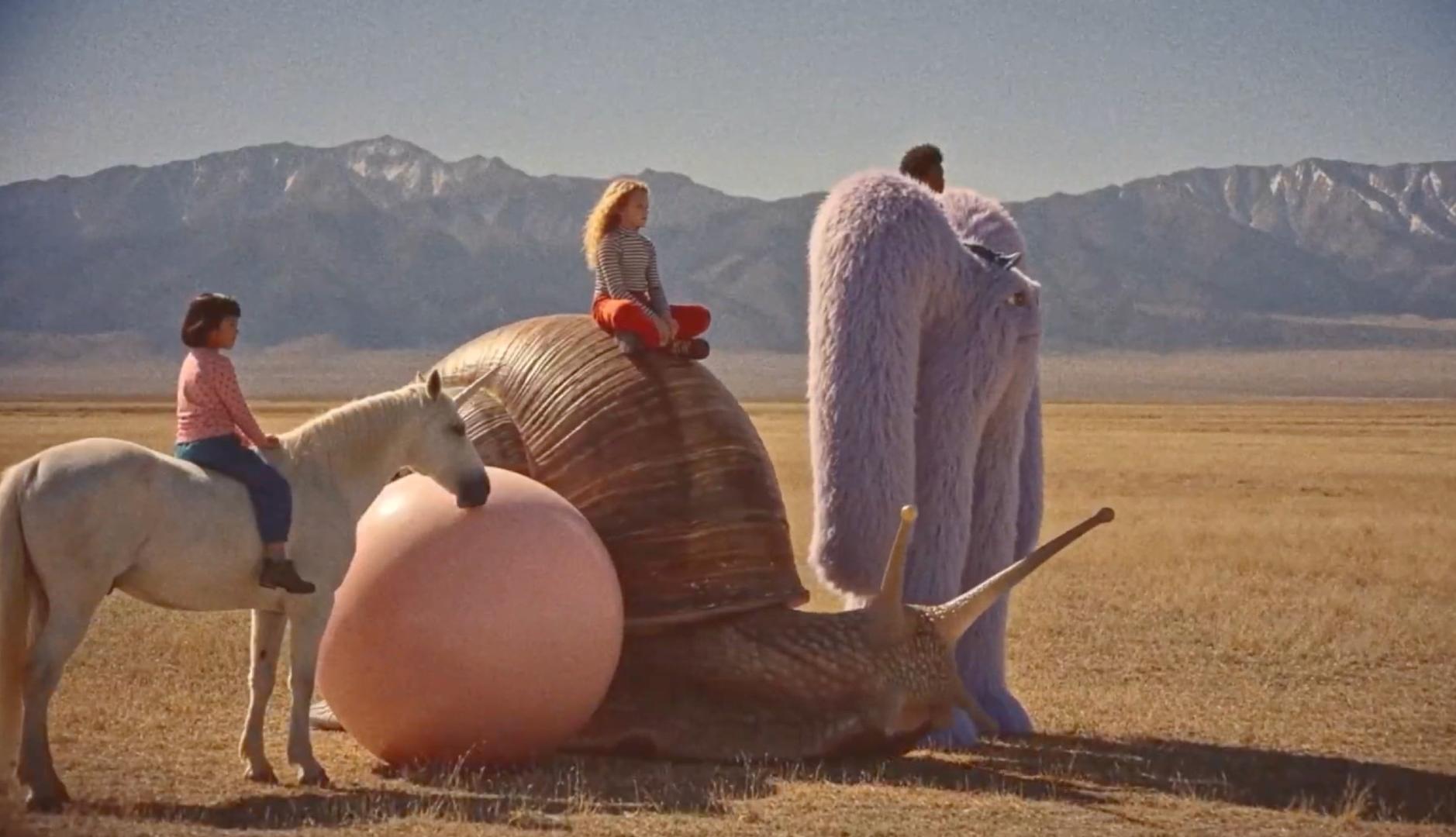 Personajes infantiles sobre un caballo, un caracol gigante y una criatura violeta en el desierto ficticio de Go North.