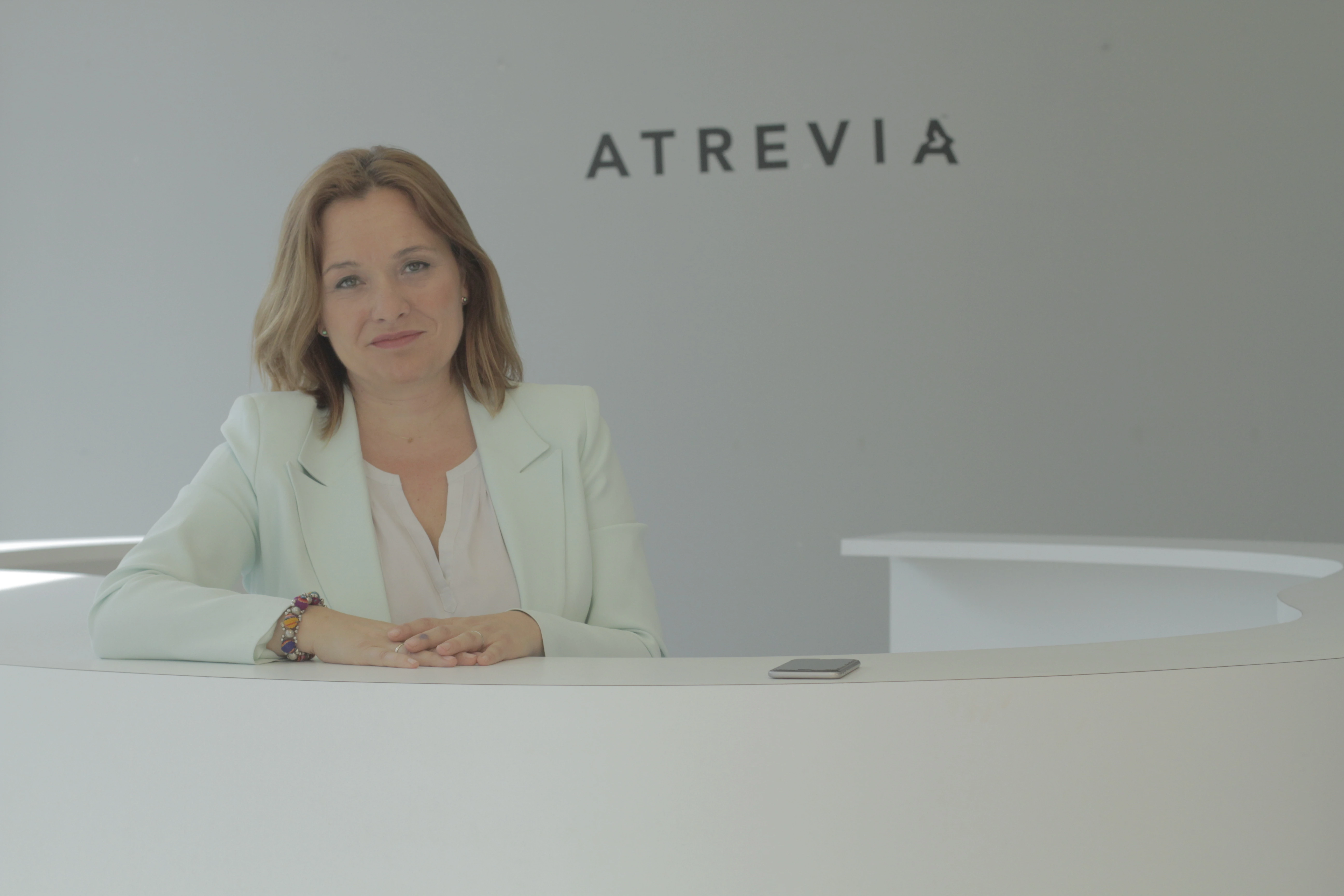 Asunción Soriano posa sentada en la recepción de ATREVIA.