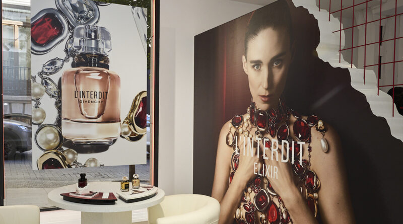 Interior de la activación de Givenchy con mesa de fragancias, butacas y grandes imágenes de campaña.