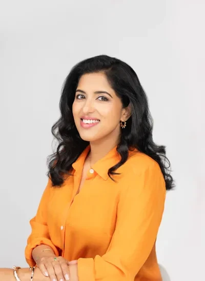 Vidhya Srinivasan posa con una camisa naranja ante un fondo claro.