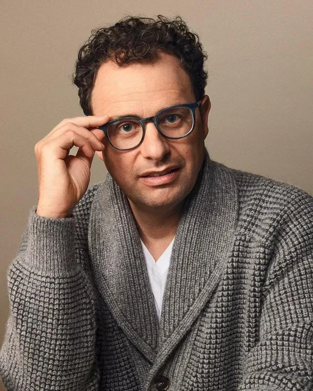 Dario Amodei posa con gafas y camisa de cuadros.