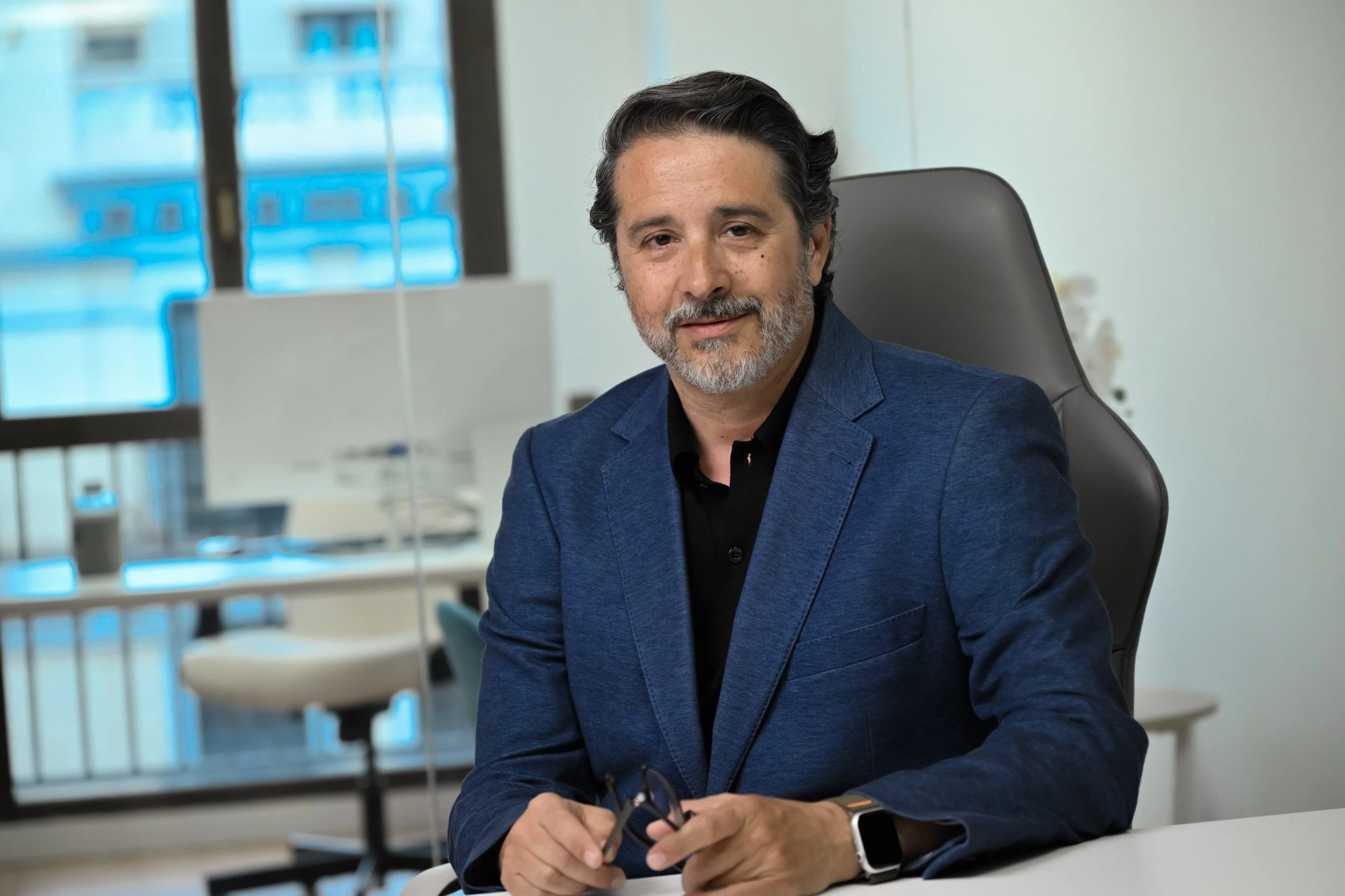 David Sandoval posa sentado a una mesa en una oficina.